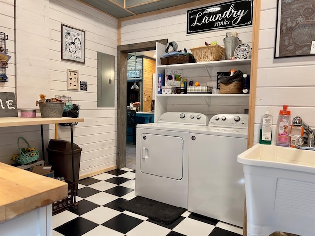 laundry room with wood walls, sink, electric panel, and washing machine and clothes dryer