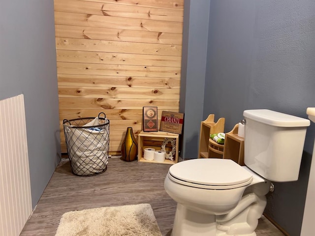 bathroom featuring toilet, wood-type flooring, and wooden walls