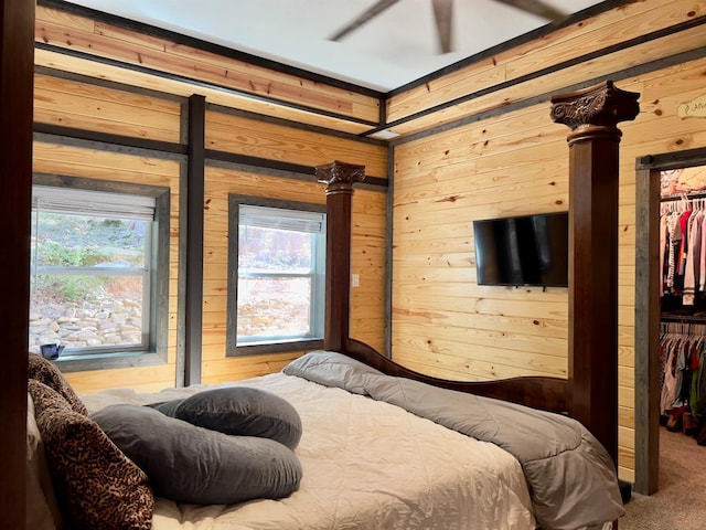 bedroom with multiple windows, wood walls, carpet, and ceiling fan