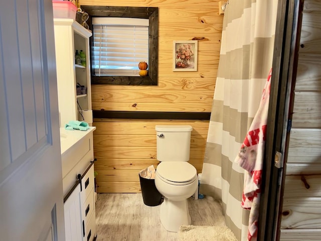 bathroom featuring wood-type flooring, vanity, toilet, and wood walls
