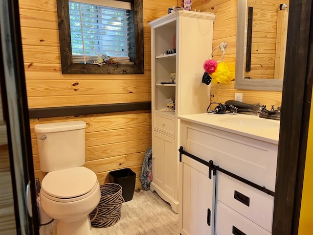 bathroom with wooden walls, toilet, vanity, and hardwood / wood-style flooring