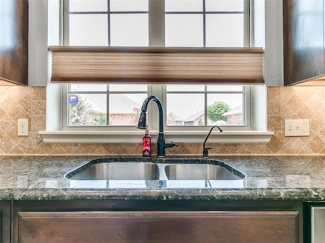 kitchen with sink, dark brown cabinets, and dark stone countertops