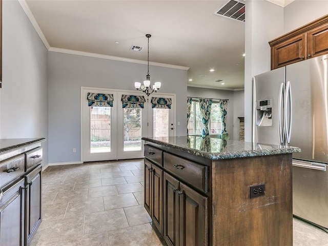 kitchen with a wealth of natural light, stainless steel fridge, a center island, and a chandelier