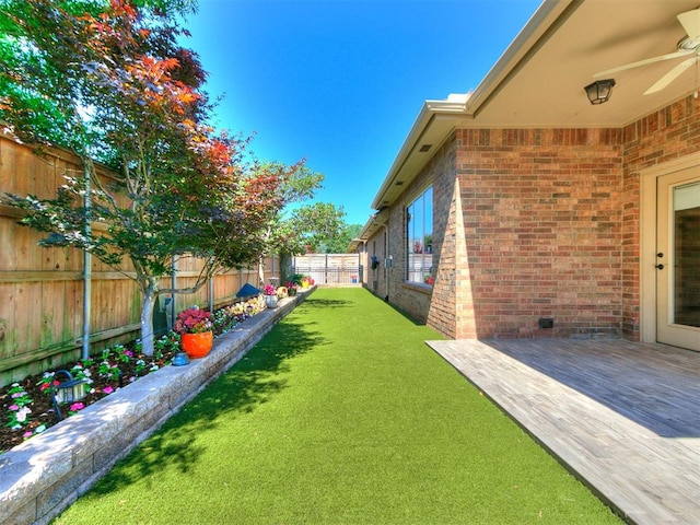 view of yard with ceiling fan and a deck