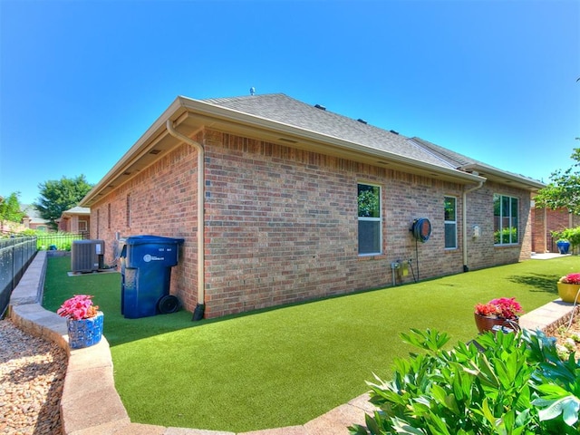 view of side of property featuring central AC unit and a lawn