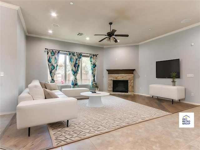 living room with ceiling fan, ornamental molding, and a stone fireplace