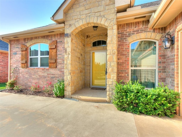 view of exterior entry with stone siding and brick siding