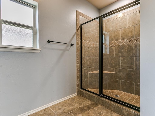 full bathroom with a shower stall and baseboards