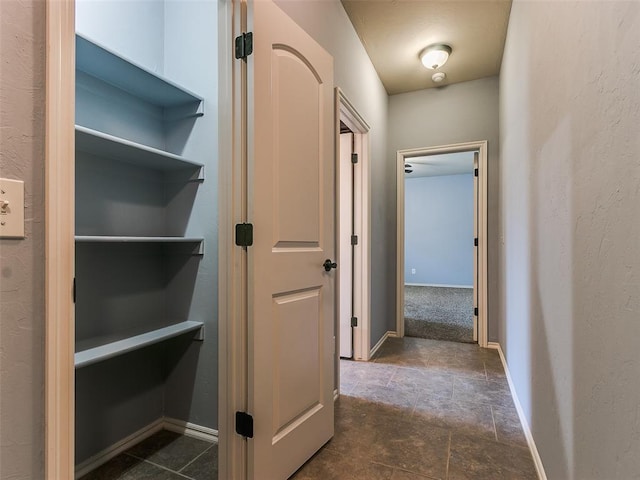 hall featuring stone finish floor and baseboards