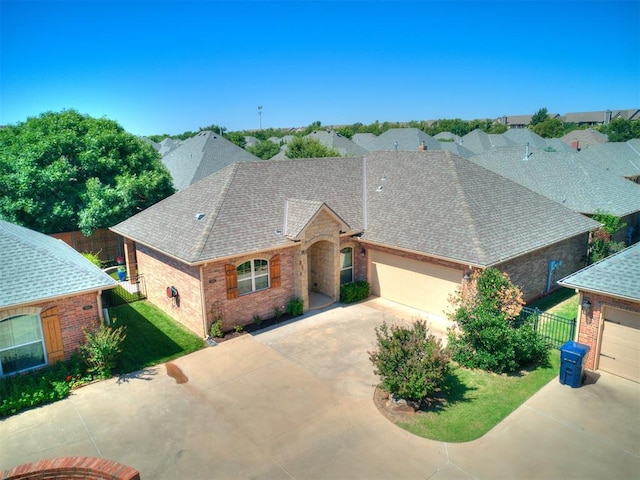 view of front of property with a garage, driveway, fence, and roof with shingles