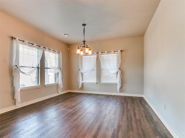 empty room featuring dark hardwood / wood-style flooring and an inviting chandelier