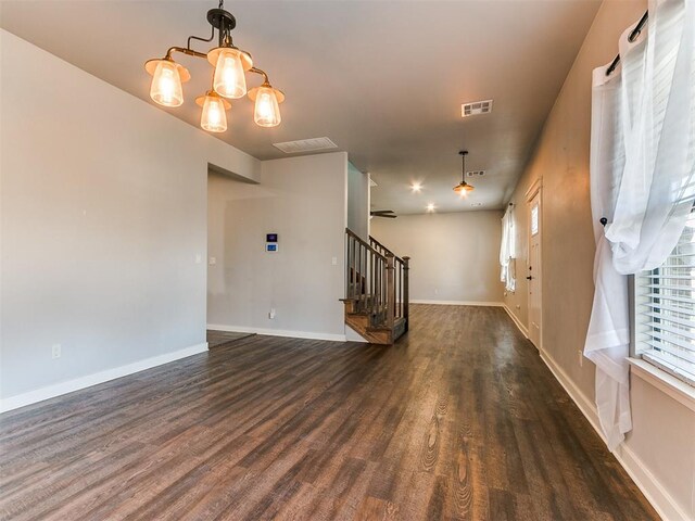 unfurnished living room featuring dark hardwood / wood-style floors and an inviting chandelier