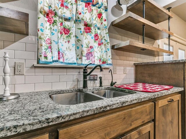 kitchen featuring light stone counters, sink, and tasteful backsplash