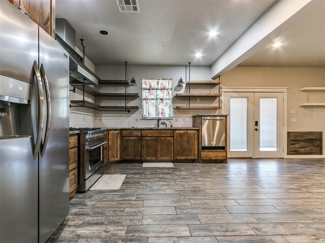 kitchen featuring dark stone counters, sink, dark hardwood / wood-style floors, tasteful backsplash, and stainless steel appliances