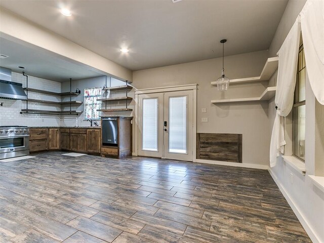 kitchen featuring high end range, backsplash, dark wood-type flooring, wall chimney range hood, and decorative light fixtures