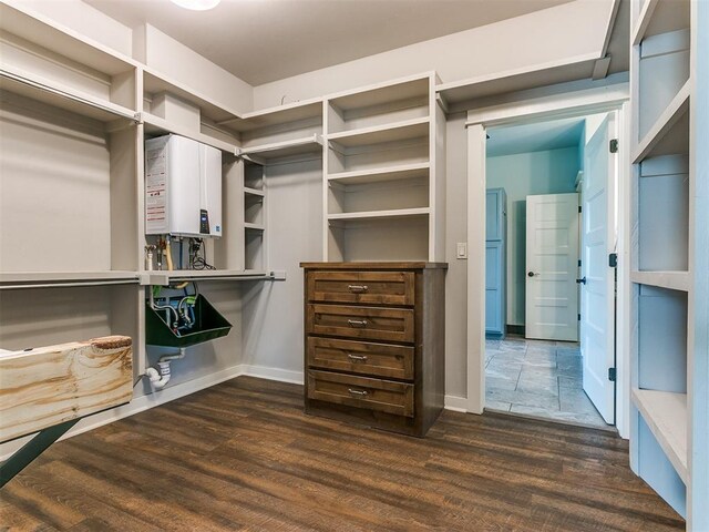 spacious closet with tankless water heater and dark hardwood / wood-style flooring