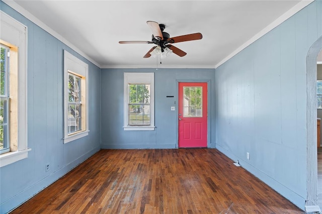 spare room featuring wooden walls, crown molding, ceiling fan, and dark wood-type flooring