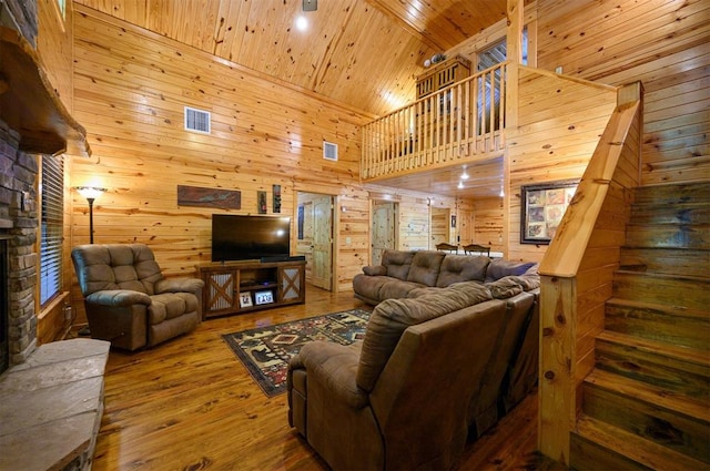 living room featuring a high ceiling, wood-type flooring, wooden walls, a fireplace, and wood ceiling