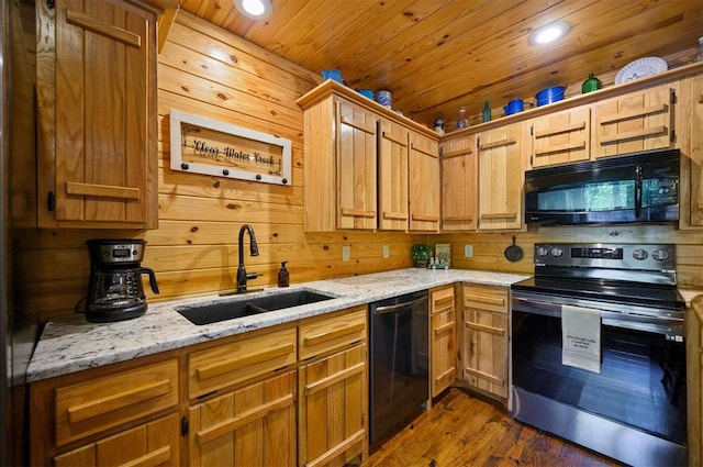 kitchen with wood walls, black appliances, sink, dark hardwood / wood-style floors, and light stone counters