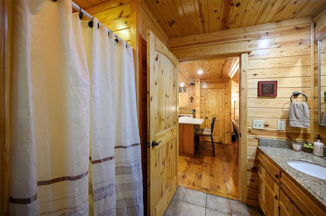 bathroom with tile patterned flooring, vanity, wood ceiling, and wooden walls