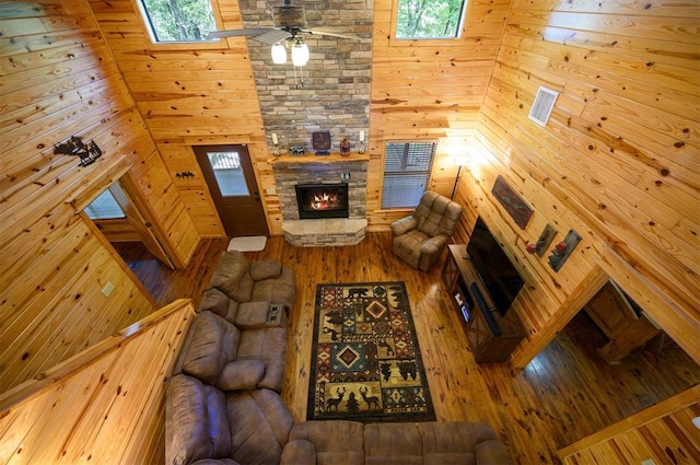 unfurnished living room with hardwood / wood-style flooring, ceiling fan, and wood walls