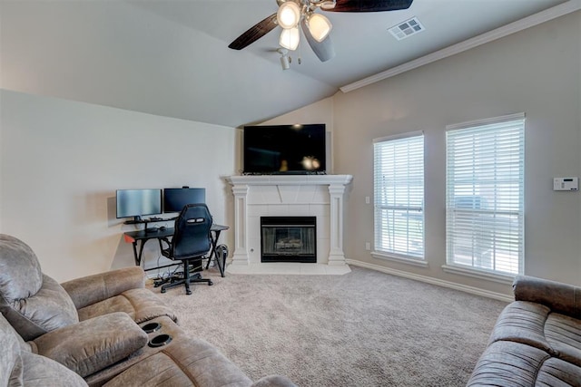 carpeted living room with ceiling fan, ornamental molding, and a tiled fireplace