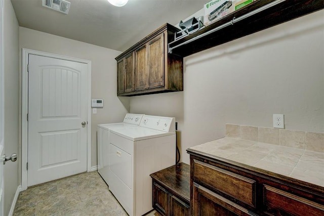 clothes washing area with cabinets and separate washer and dryer