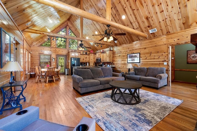 living room featuring light hardwood / wood-style floors, high vaulted ceiling, ceiling fan, and wooden walls