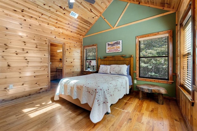 bedroom with wood walls, light hardwood / wood-style floors, wooden ceiling, and high vaulted ceiling