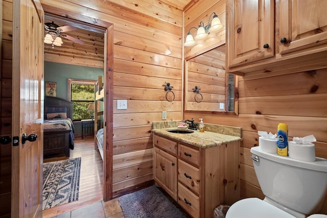 bathroom with vanity, ceiling fan, wooden walls, wood-type flooring, and toilet