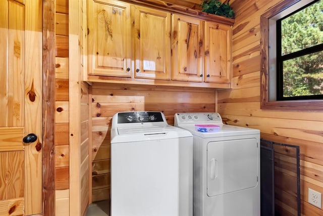 laundry room with separate washer and dryer, wooden walls, and cabinets