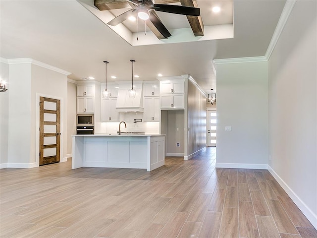 kitchen with appliances with stainless steel finishes, ceiling fan, a center island with sink, light hardwood / wood-style flooring, and white cabinetry