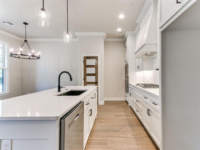 kitchen with sink, stainless steel appliances, an island with sink, decorative light fixtures, and custom exhaust hood