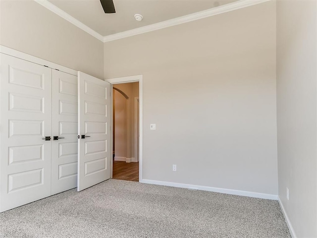 unfurnished bedroom featuring carpet flooring, a closet, crown molding, and ceiling fan