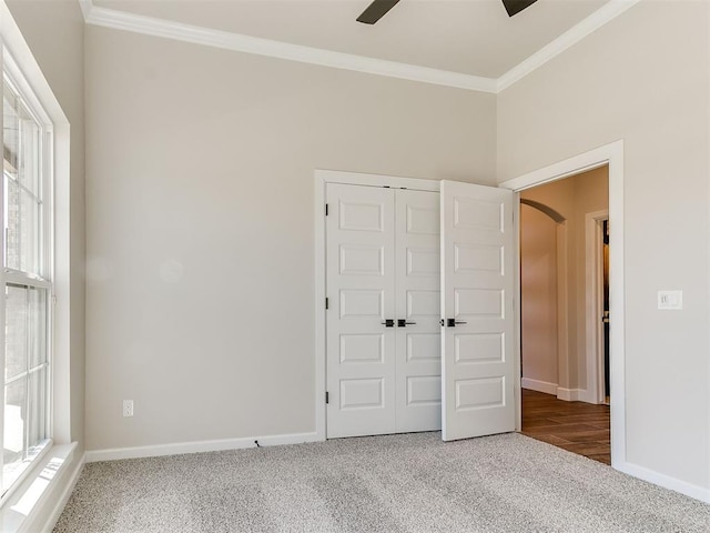 unfurnished bedroom with ceiling fan, carpet floors, crown molding, and a closet