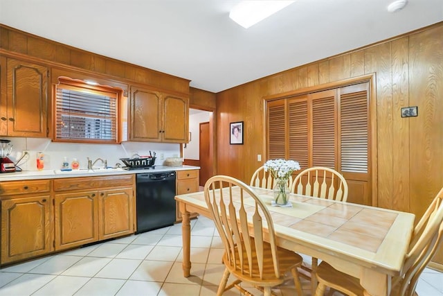 kitchen featuring dishwasher, light tile patterned floors, wooden walls, and sink