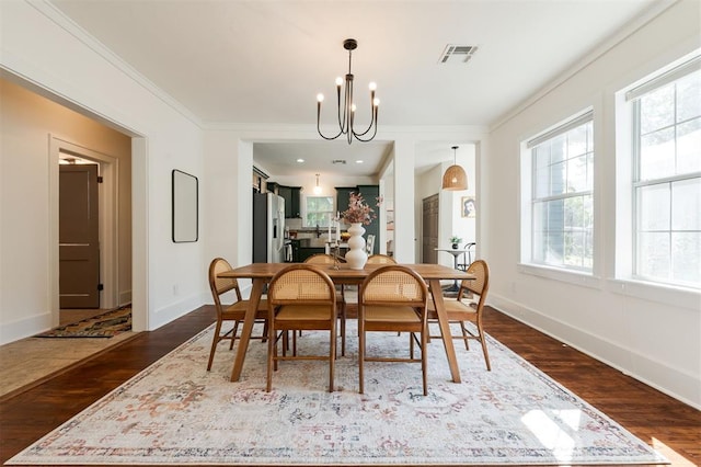 dining area with a notable chandelier, dark hardwood / wood-style flooring, and ornamental molding