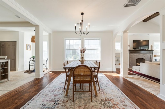 dining area with a brick fireplace, an inviting chandelier, lofted ceiling, and light hardwood / wood-style flooring