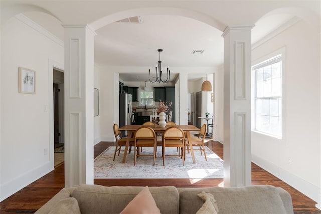 dining room with decorative columns, a chandelier, dark hardwood / wood-style floors, and ornamental molding