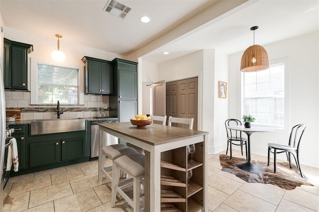 kitchen with dishwasher, sink, hanging light fixtures, green cabinets, and backsplash