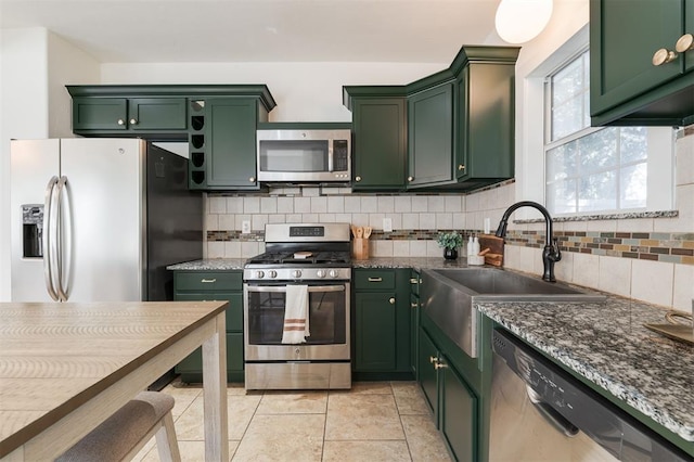 kitchen with tasteful backsplash, green cabinets, dark stone counters, and appliances with stainless steel finishes