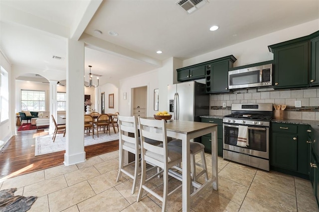 kitchen featuring appliances with stainless steel finishes, backsplash, light hardwood / wood-style flooring, and green cabinets