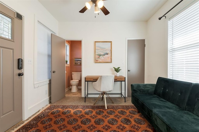 carpeted office with plenty of natural light and ceiling fan