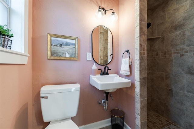 bathroom featuring a tile shower, toilet, and sink