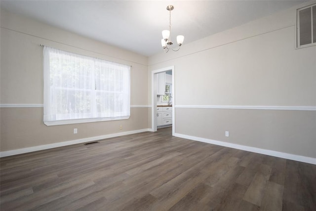 spare room featuring dark hardwood / wood-style floors and a notable chandelier