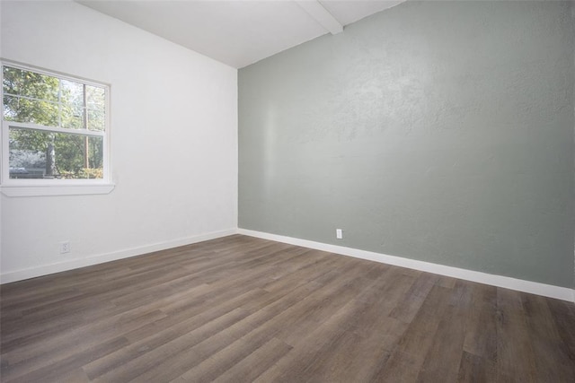 empty room with beam ceiling and dark wood-type flooring