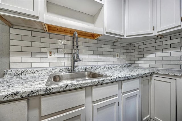 kitchen featuring white cabinetry, sink, and tasteful backsplash