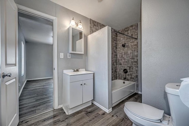 full bathroom featuring hardwood / wood-style floors, vanity, toilet, and tiled shower / bath