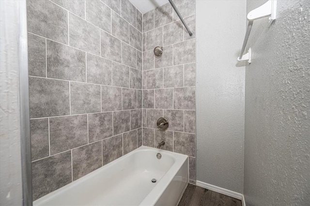 bathroom with hardwood / wood-style floors and tiled shower / bath