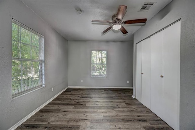 unfurnished bedroom featuring a closet, dark hardwood / wood-style floors, and ceiling fan